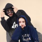 Stylish young man and woman posing in hoodies during a studio fashion shoot.