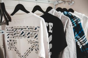 Assorted stylish male apparel hanging on plastic racks on metal beam in wardrobe