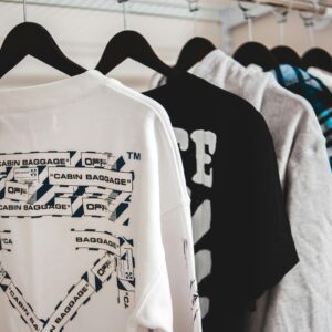 Assorted stylish male apparel hanging on plastic racks on metal beam in wardrobe